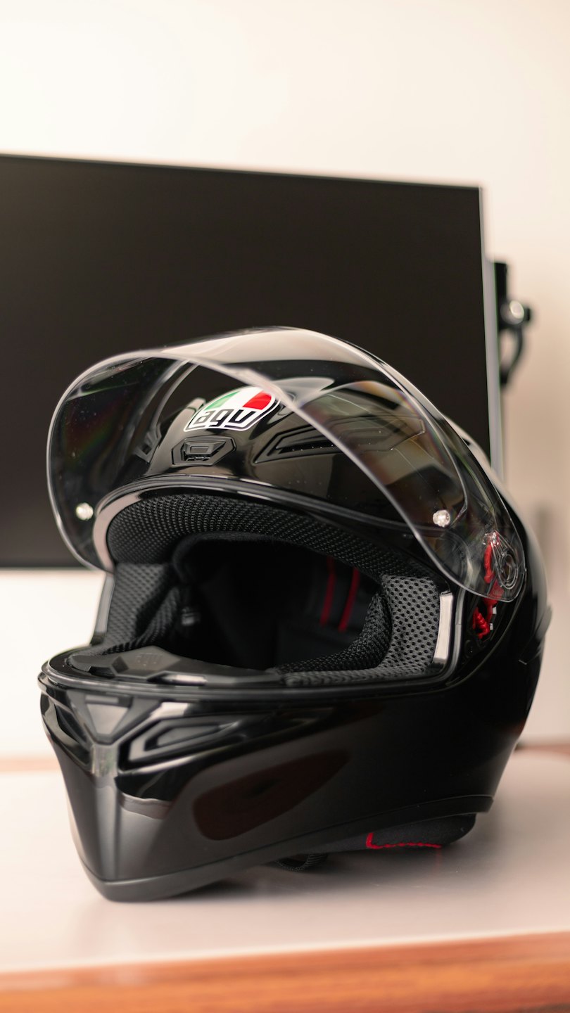 Casco da moto nero lucido su una superficie bianca pulita.