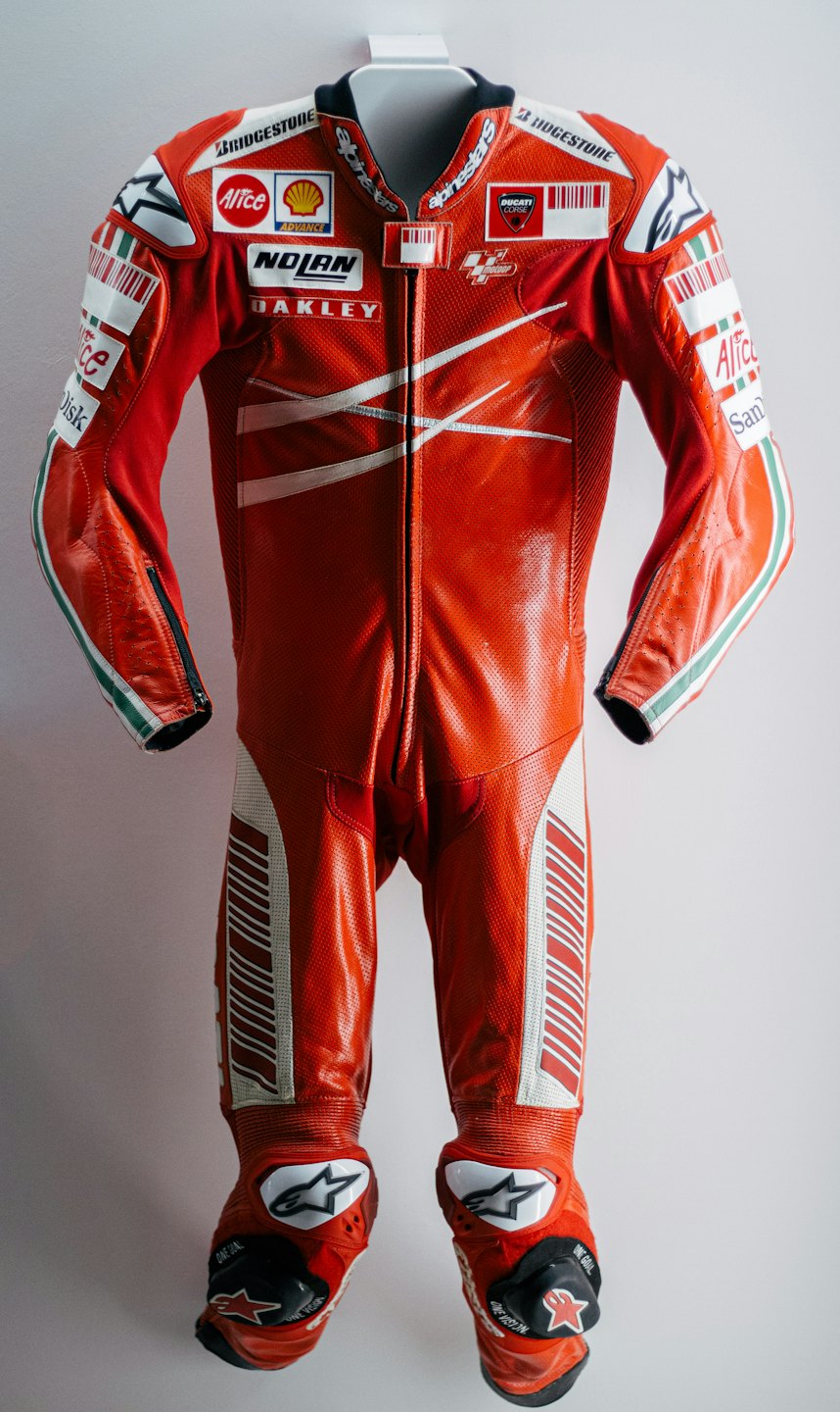 Tuta da moto da corsa in pelle rossa con loghi degli sponsor disposti verticalmente.