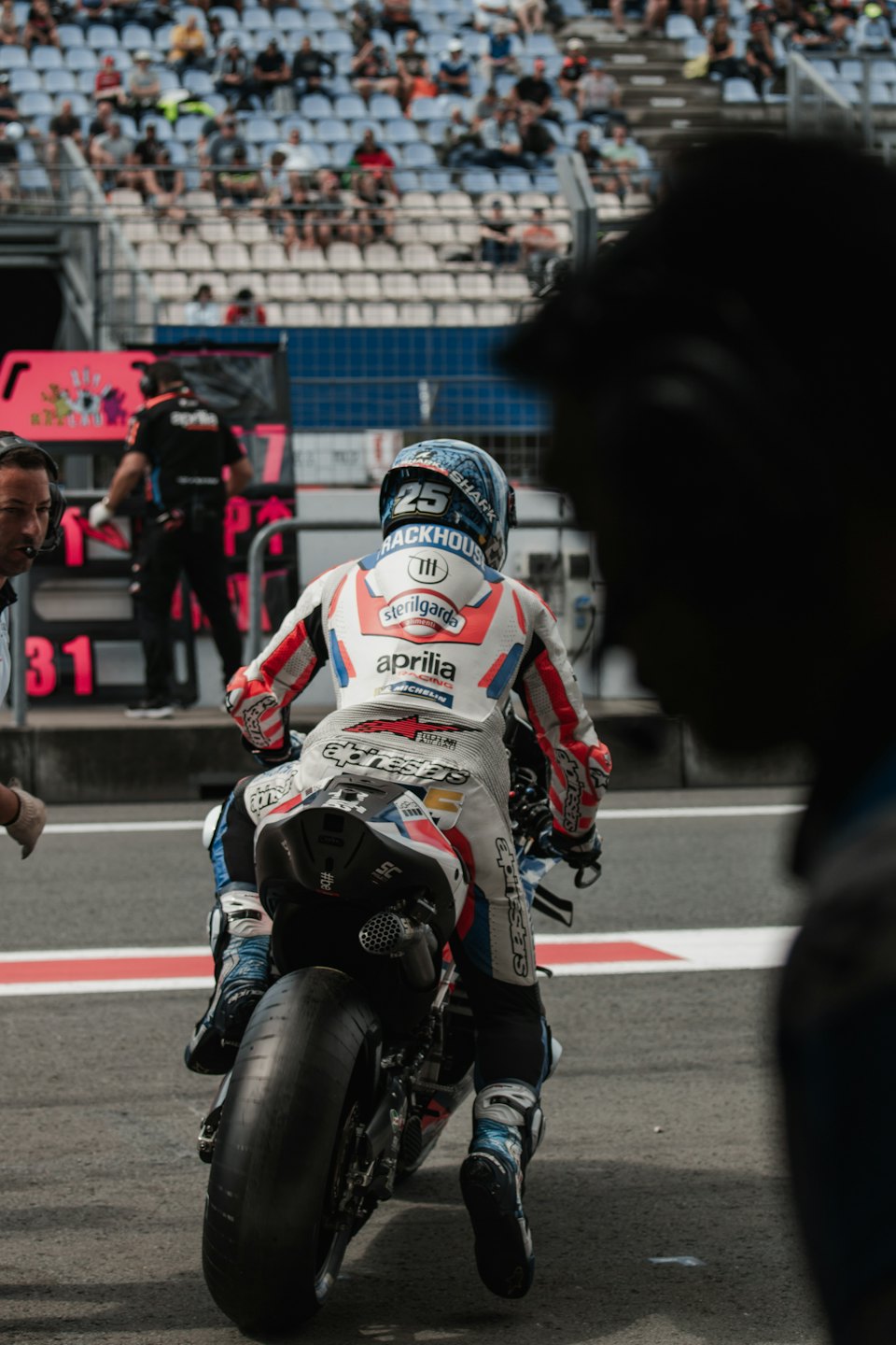 Un pilota di moto siede su una moto nella corsia dei box con un membro dell'equipaggio nelle vicinanze.