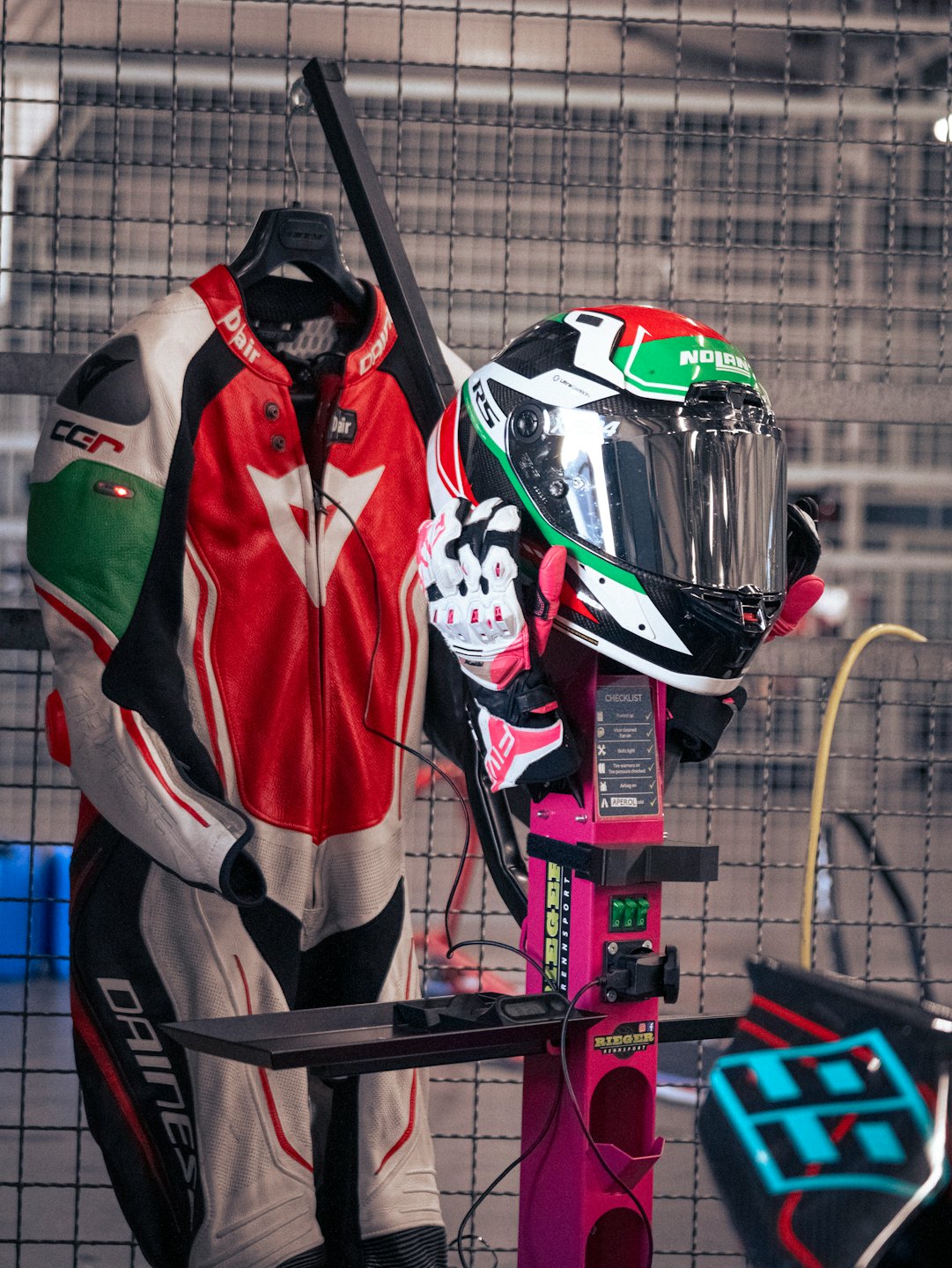 Attrezzatura da corsa per moto esposta su un supporto rosa in un'officina.